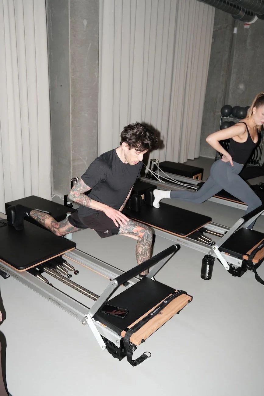 Two clients doing a lunge on reformers at Sink Reformer in Aarhus