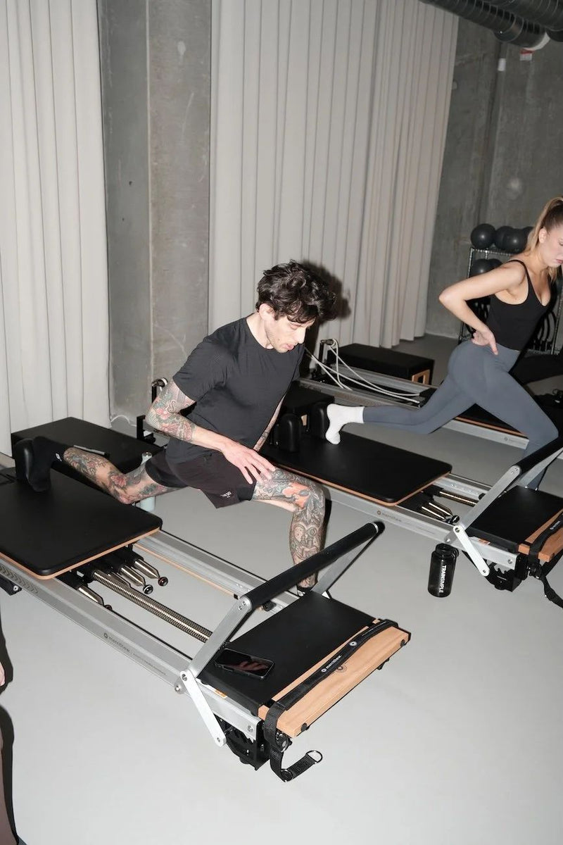 Two clients doing a lunge on reformers at Sink Reformer in Aarhus