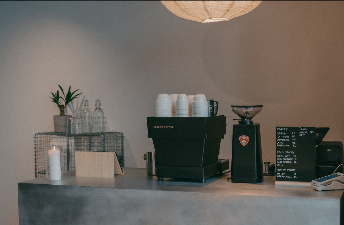 Espressomaskine og stablede kopper på cafédisken i Sink Social hos Sink Reformer