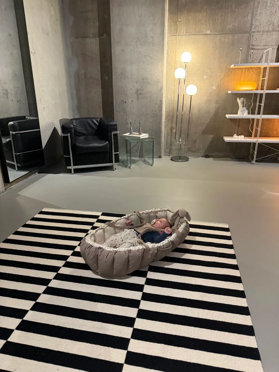 Baby resting in a baby nest on a striped rug in the studio during Sink Mama at Sink Reformer, Aarhus