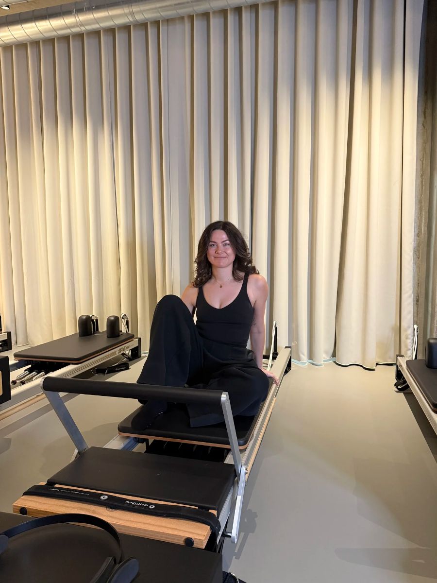 Julie, founder and reformer Pilates coach, sitting on a reformer at Sink Reformer, Aarhus