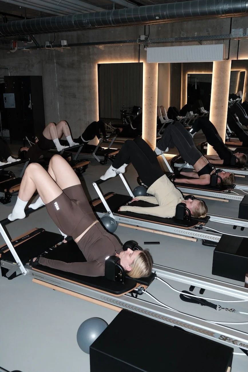 Group reformer Pilates class doing bridges in the concrete basement studio at Sink Reformer, Aarhus