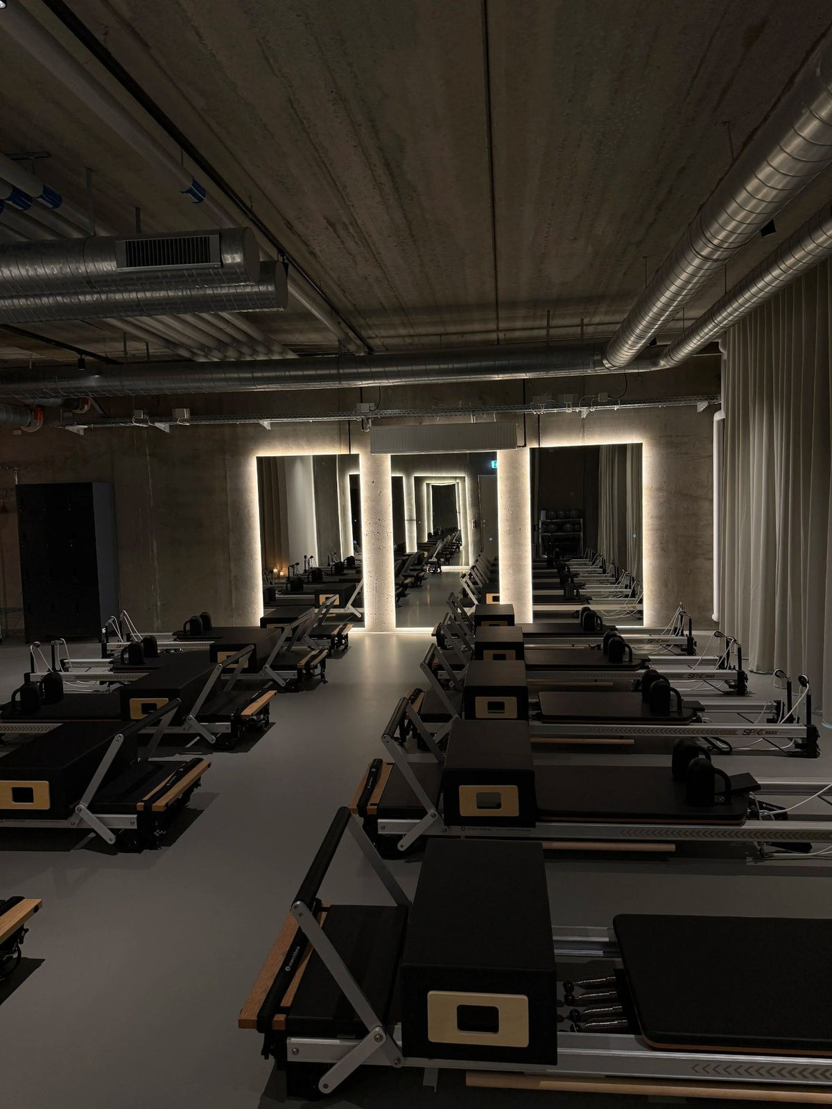 Rows of reformers in the concrete basement studio at Sink Reformer, Aarhus Ø