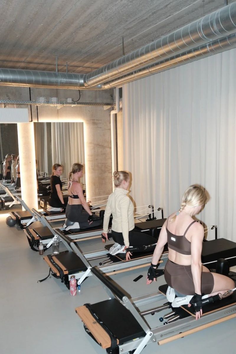 Small-group class kneeling on reformers in the bright studio at Sink Reformer, Aarhus
