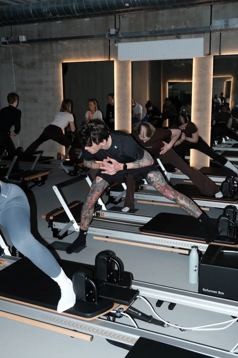 Man and women doing a lunge on reformers during a class at Sink Reformer in Aarhus
