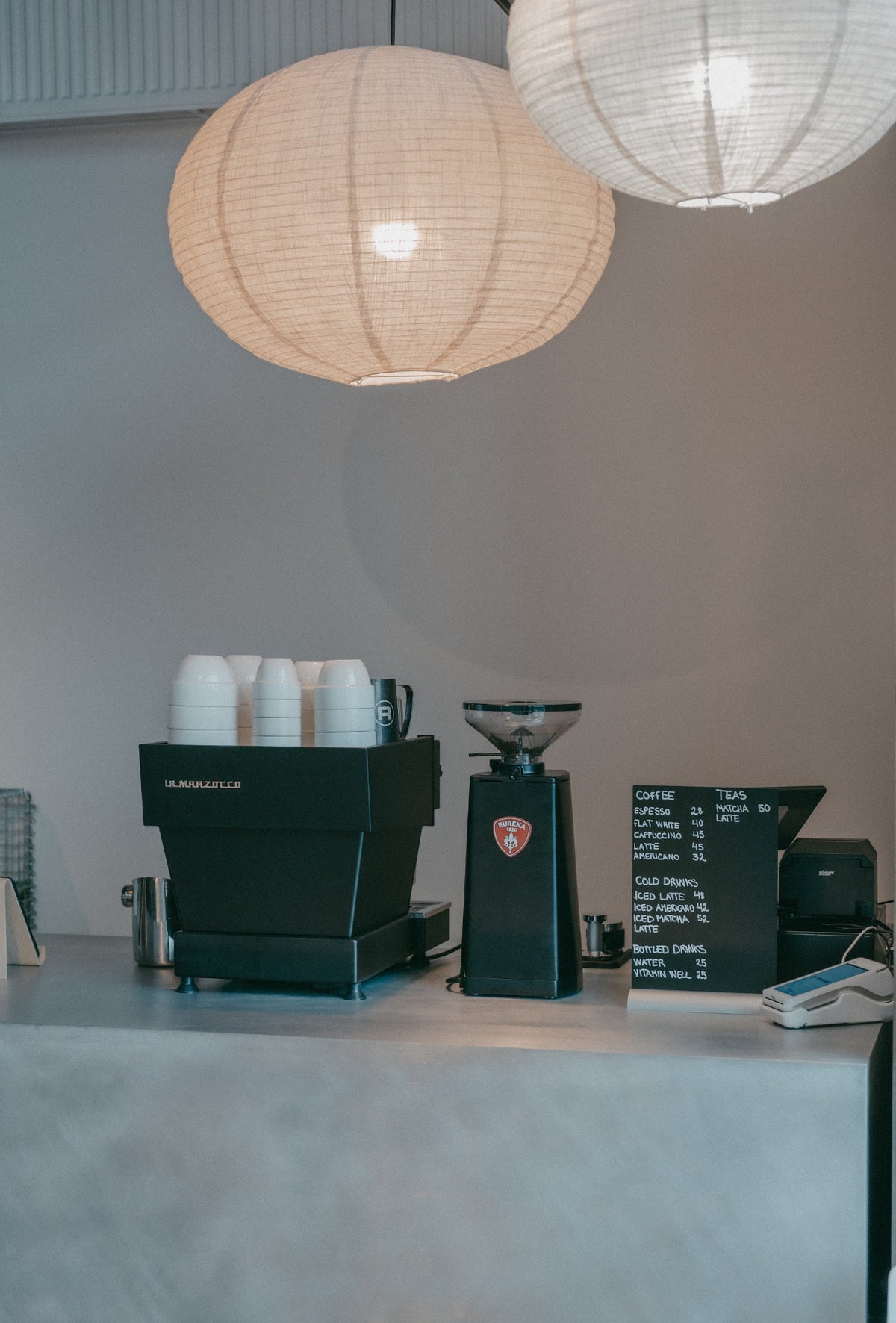 Coffee bar with espresso machine, grinder and menu board under paper lanterns at Sink Social, Aarhus Ø