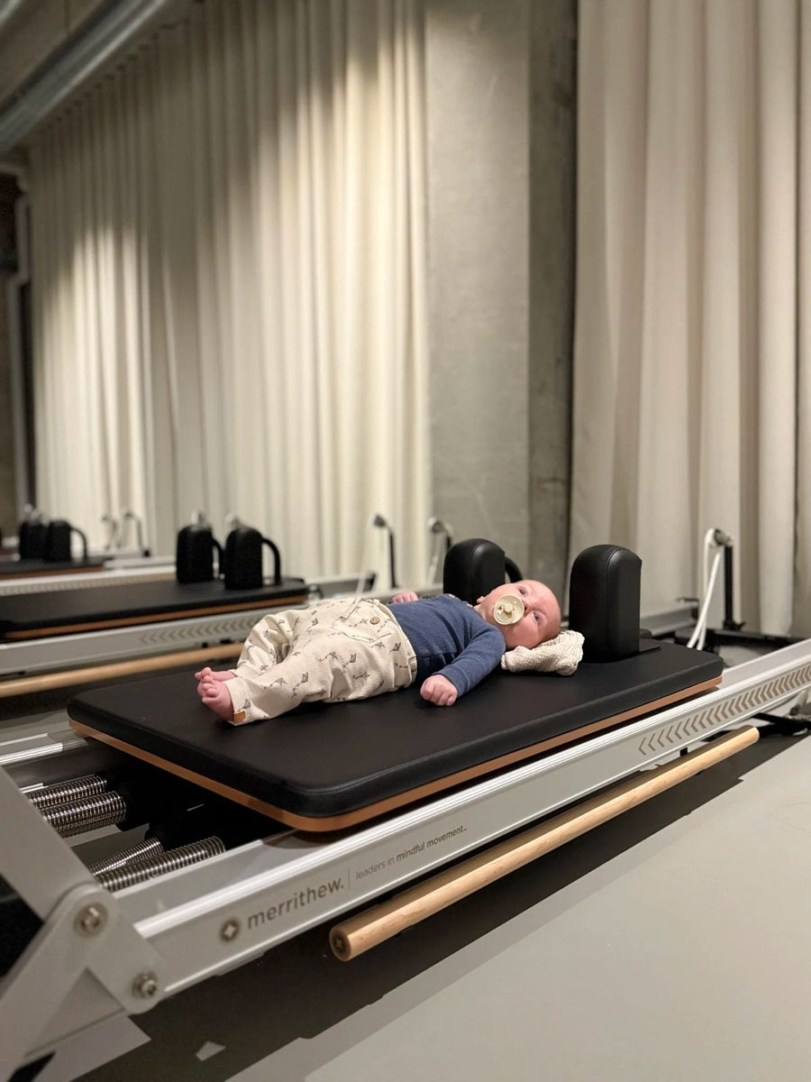 Baby lying on a Merrithew reformer during the Sink Mama mother and baby class at Sink Reformer, Aarhus