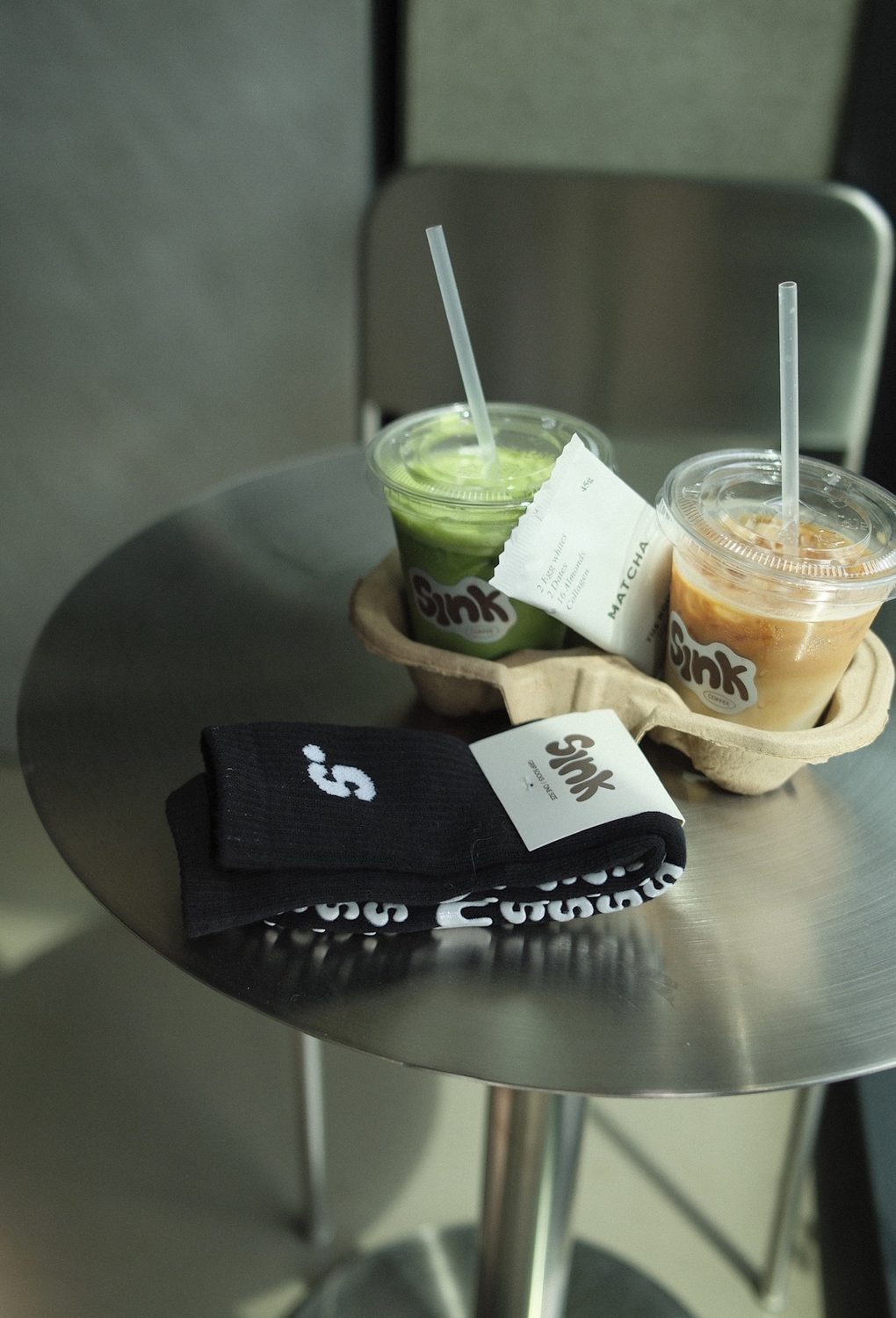 Iced matcha and iced latte in Sink cups with Sink grip socks on a café table at Sink Reformer, Aarhus