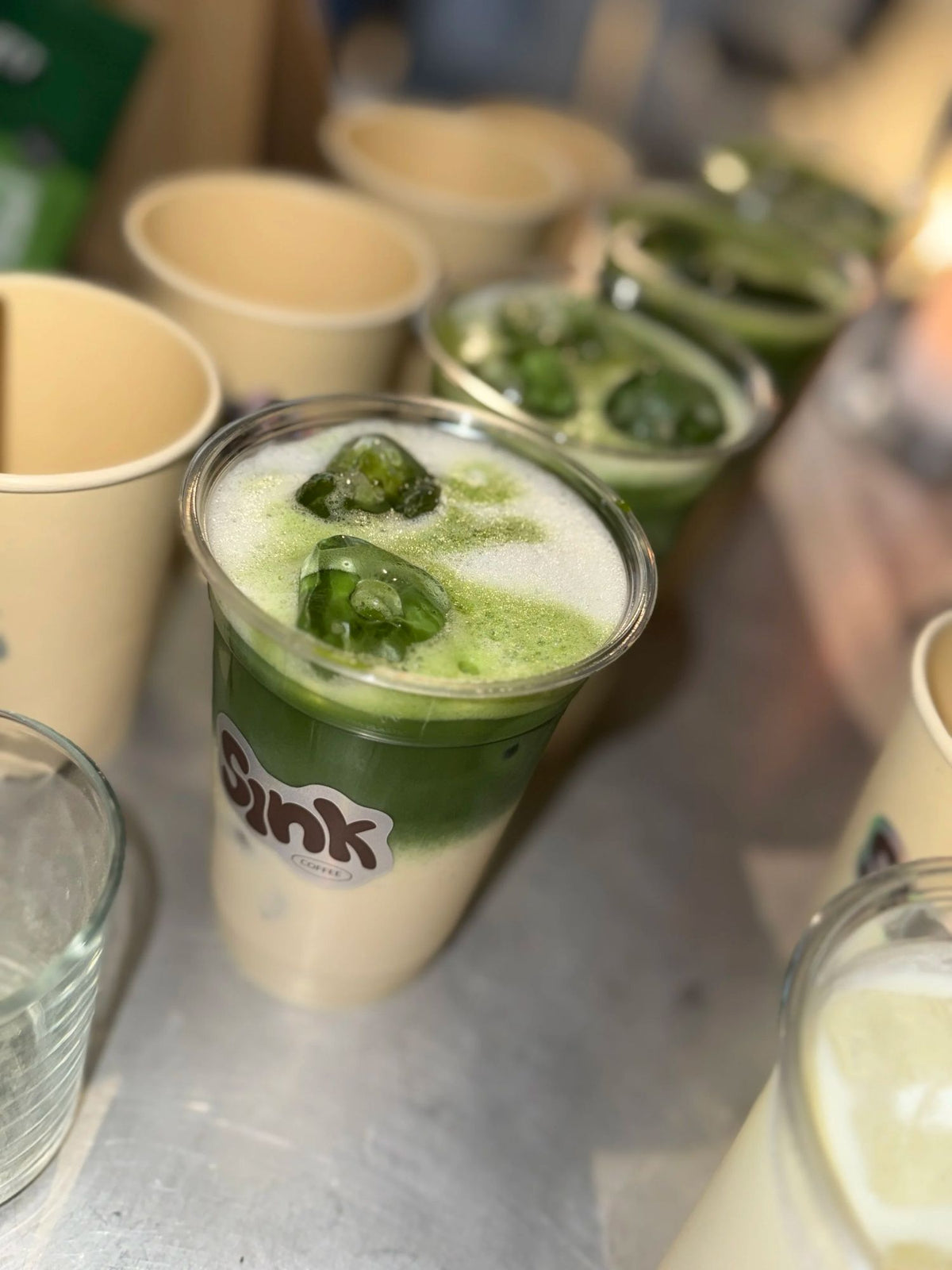 Iced matcha lattes i Sink-kopper sat på række til et event hos Sink Reformer