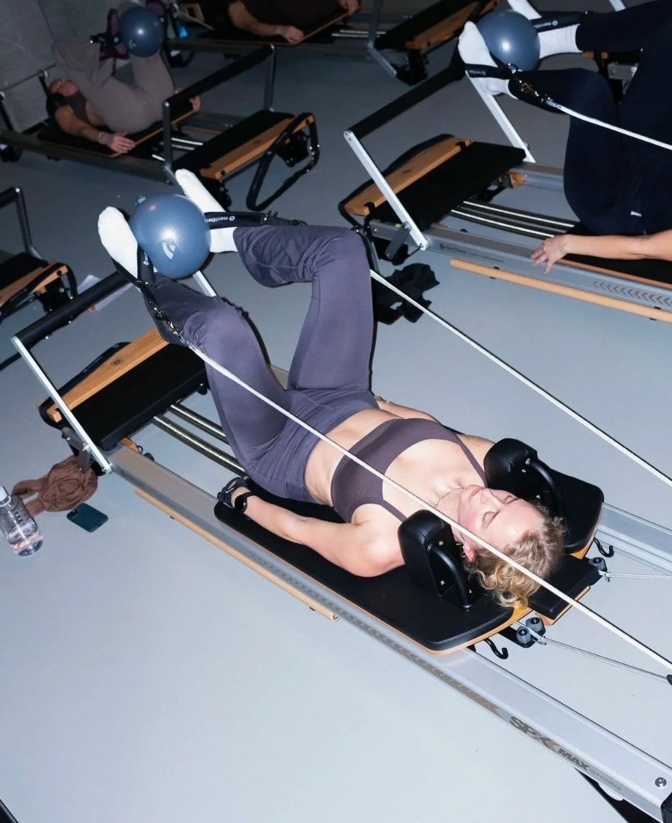 Client lying on a reformer with a ball between her feet during a class at Sink Reformer, Aarhus